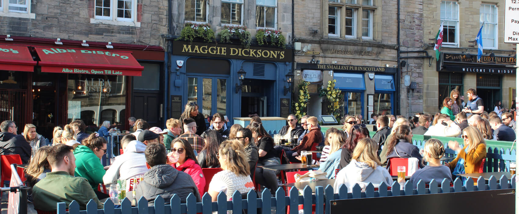 Exterior of Maggie Dicksons pub with people sitting in outside seating